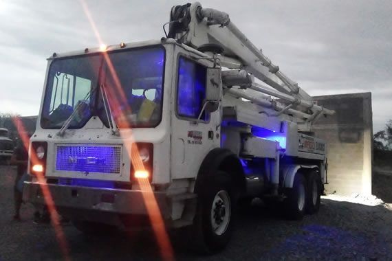 Un camión bomba de hormigón está iluminado con luces azules.