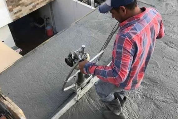 Un hombre está trabajando en un piso de concreto con una máquina.