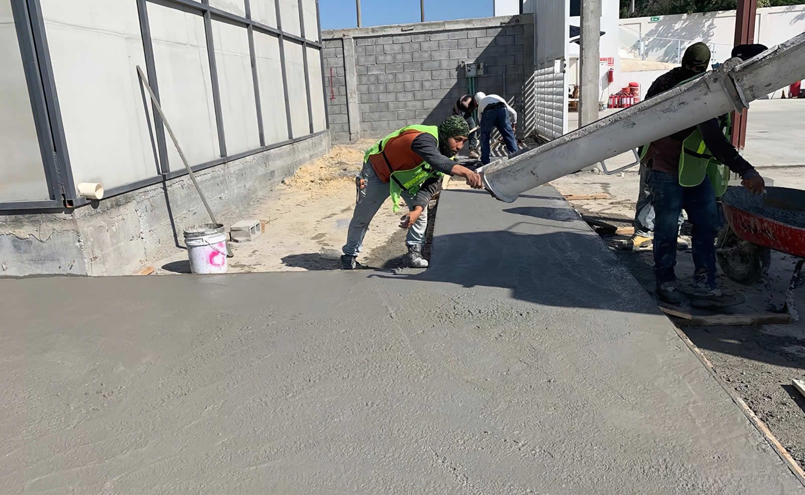 Un grupo de trabajadores de la construcción está vertiendo hormigón en una acera.