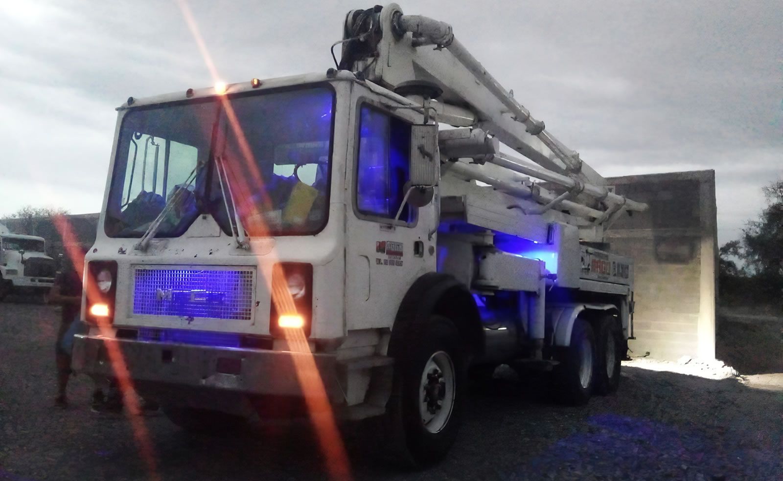 Un camión bomba de hormigón está iluminado con luces azules.