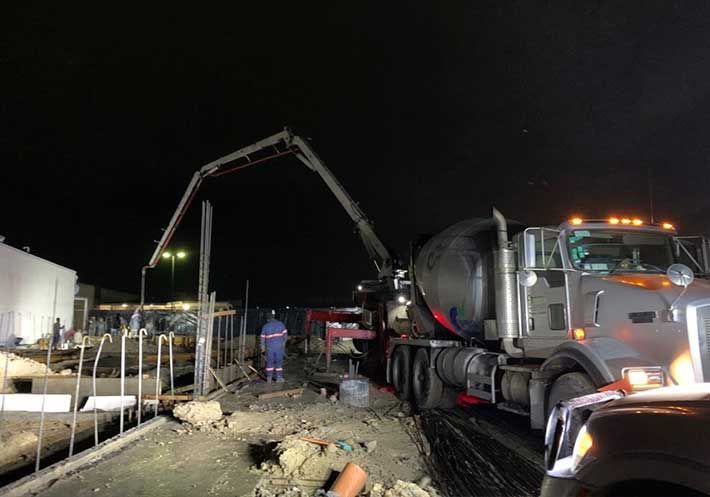 Un camión de hormigón está vertiendo hormigón en un agujero por la noche.
