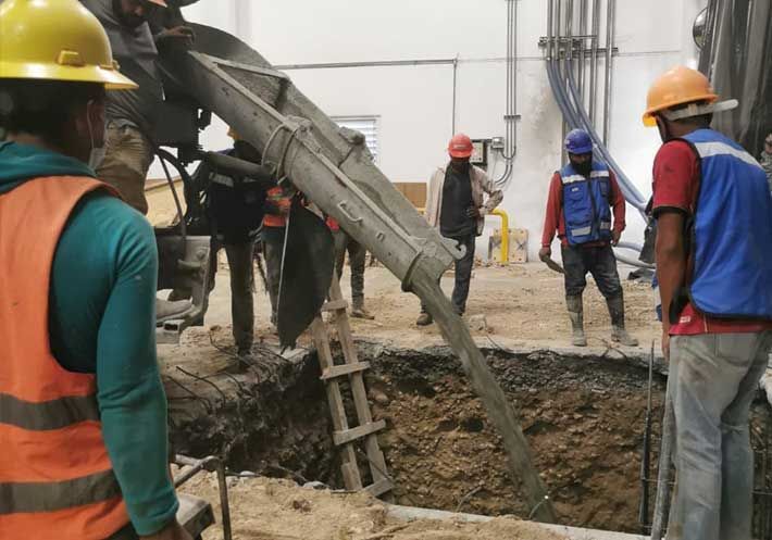 Un grupo de trabajadores de la construcción está vertiendo hormigón en un agujero.