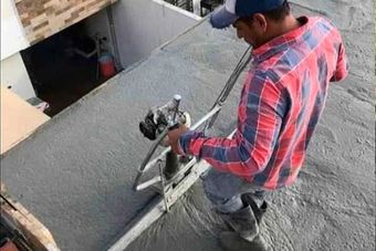 Un hombre está trabajando en un piso de concreto con una máquina.
