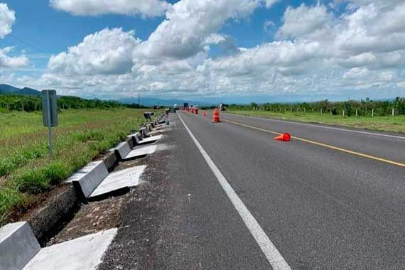 Una carretera con conos naranjas a los lados en un día soleado.