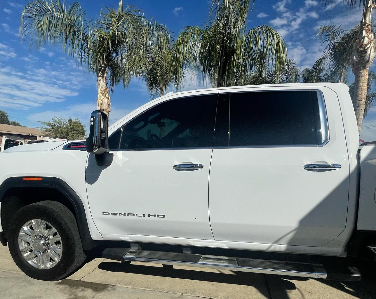 A white truck is parked in a parking lot with palm trees in the background.