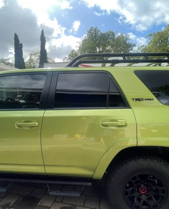 A green toyota suv is parked on a brick driveway