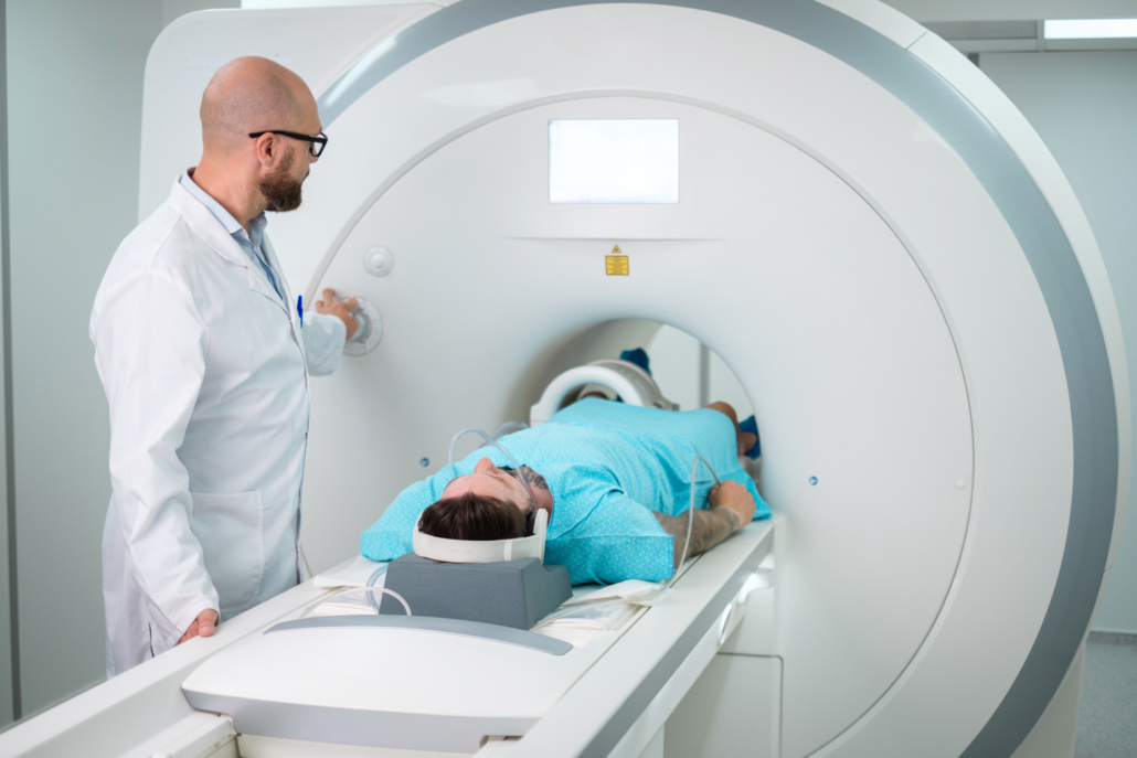 ManInMRIScanner A doctor is standing next to a patient laying in a mri machine.
