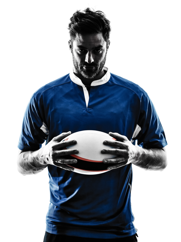 A man in a blue shirt is holding a rugby ball in his hands.