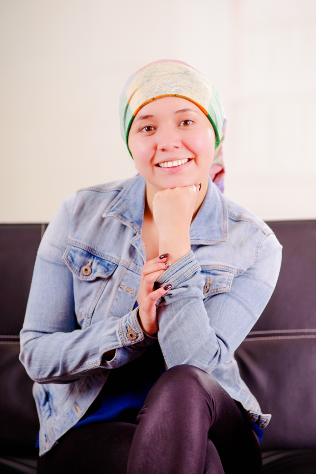 A woman wearing a head scarf and a denim jacket is sitting on a couch.