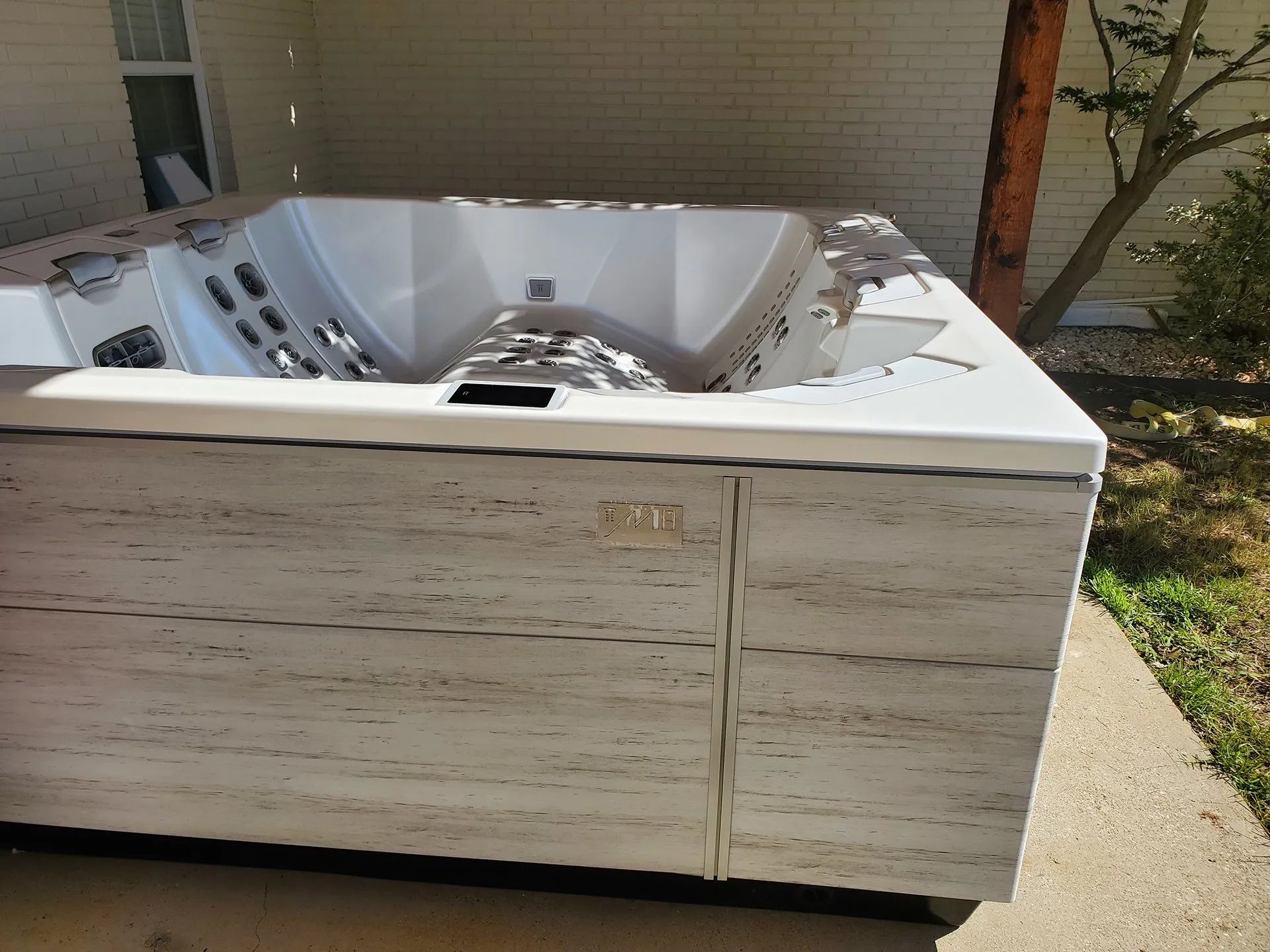 A white hot tub is sitting on the sidewalk in front of a house.