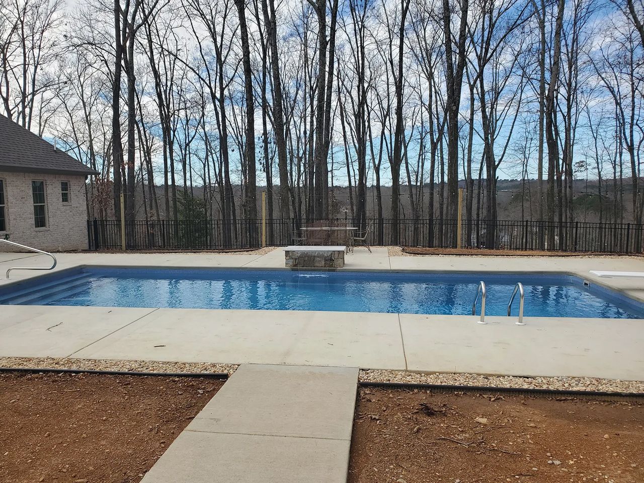 A large swimming pool is surrounded by trees on a sunny day