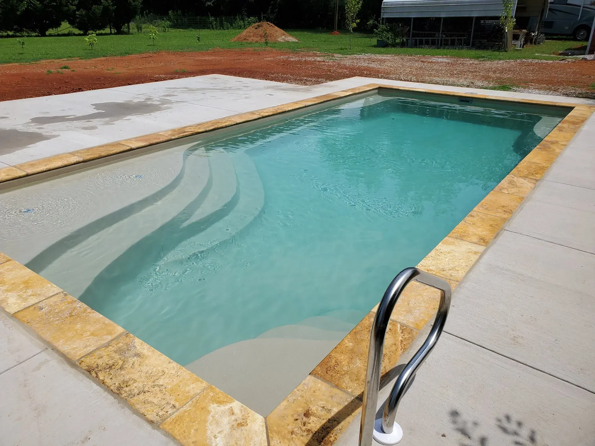 A large swimming pool with stairs and a metal ladder