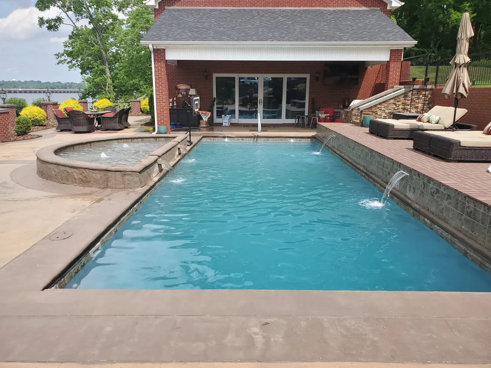 There is a large swimming pool in the backyard of a house.