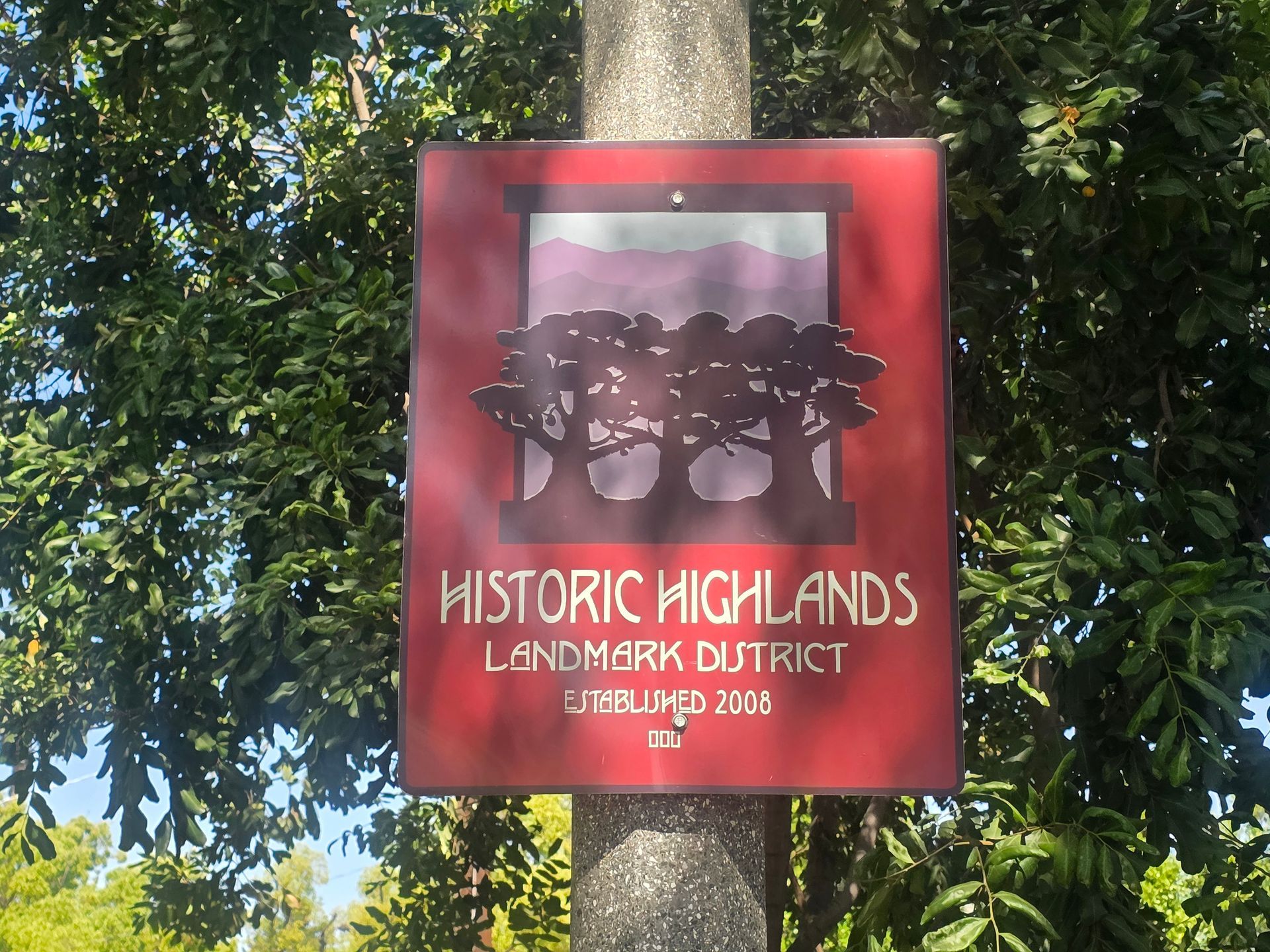 Sign for Historic Highlands Landmark District, red with stylized trees and mountains.