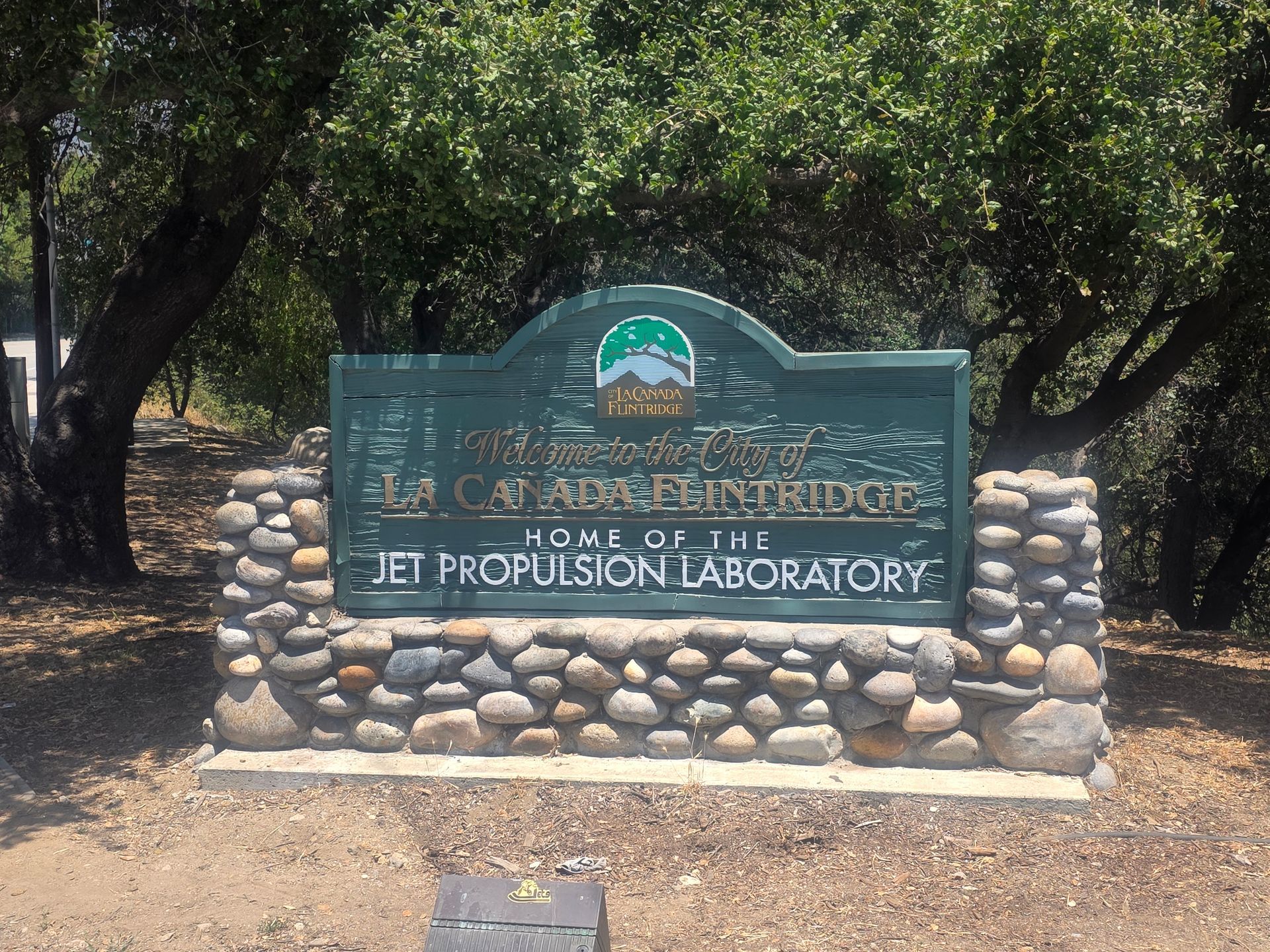 Sign for the Jet Propulsion Laboratory, green with stone base, under trees, reads
