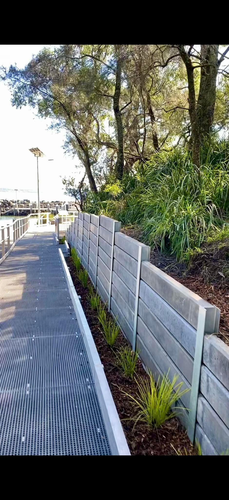 A Walkway Next to a Retaining Wall With Trees — ALI Civil Pty Ltd in South Ulladulla, NSW