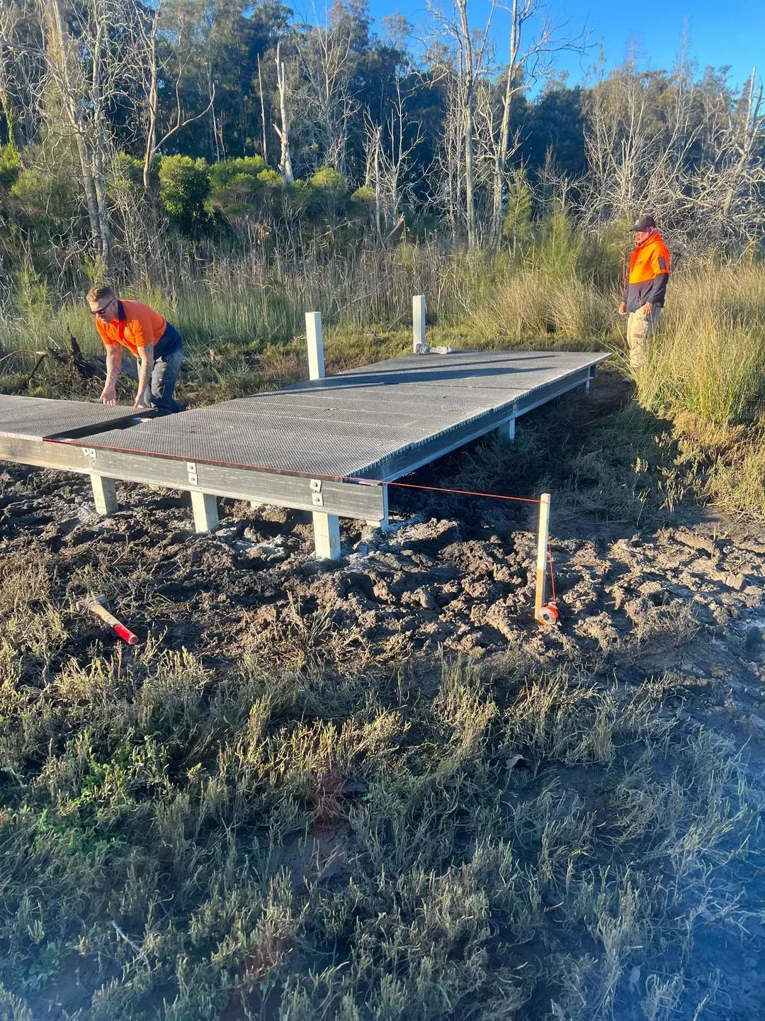 Two Workers in Orange Vests on a Low Wooden Boardwalk Platform — ALI Civil Pty Ltd in South Nowra, NSW
