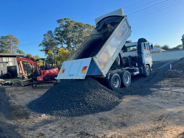 Dump truck unloading gravel at a construction site with an excavator, outdoors. — ALI Civil Pty Ltd in South Nowra, NSW