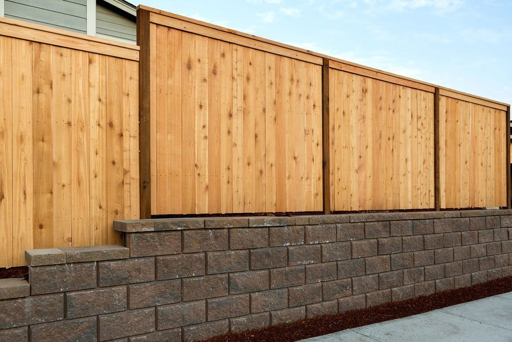 A Wooden Fence Is Sitting On Top Of A Brick Wall — AAA Fencing & Supplies in Southport, QLD