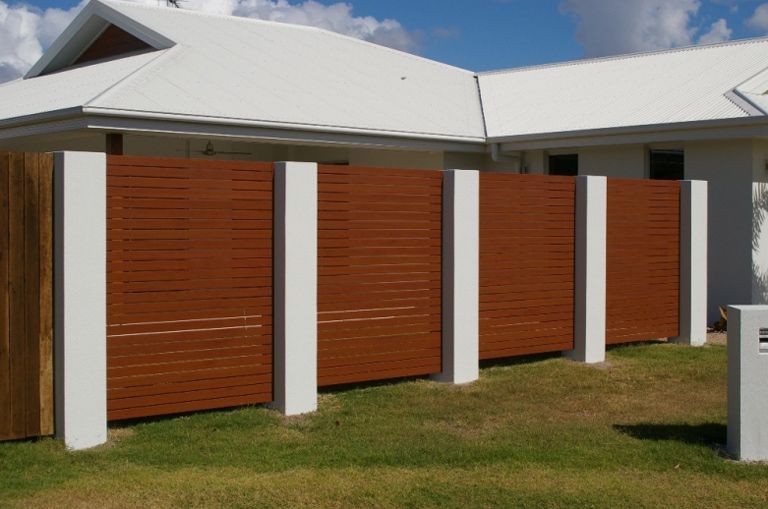 A White House With A Wooden Fence In Front Of It — AAA Fencing & Supplies in Southport, QLD