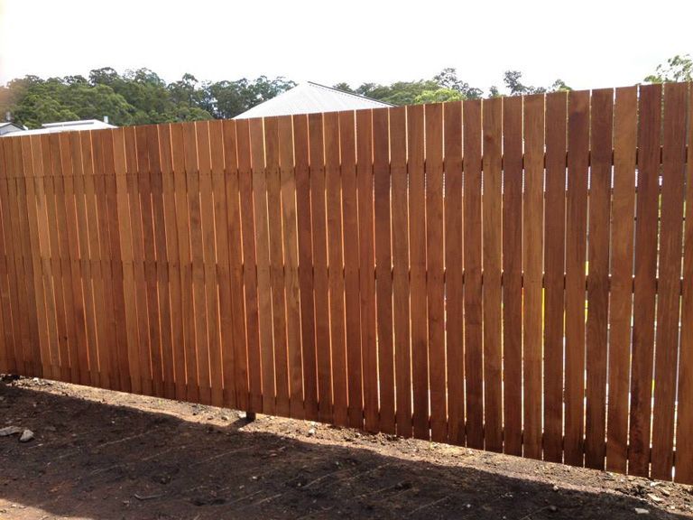 A Wooden Fence Is Sitting In The Dirt In Front Of A House — AAA Fencing & Supplies in Southport, QLD