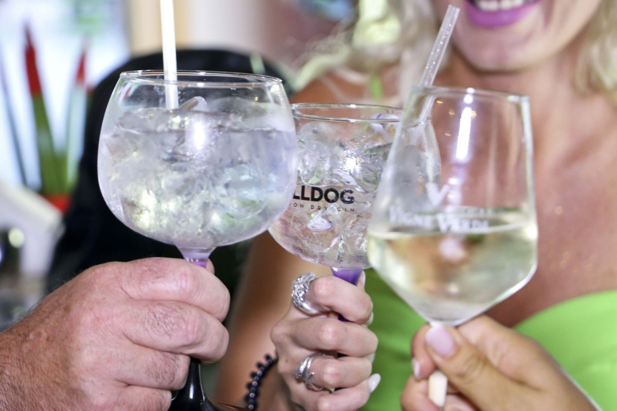 Tre persone brindano con bicchieri di cocktail e vino.