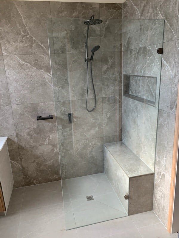 A bathroom with a walk in shower and a bench.