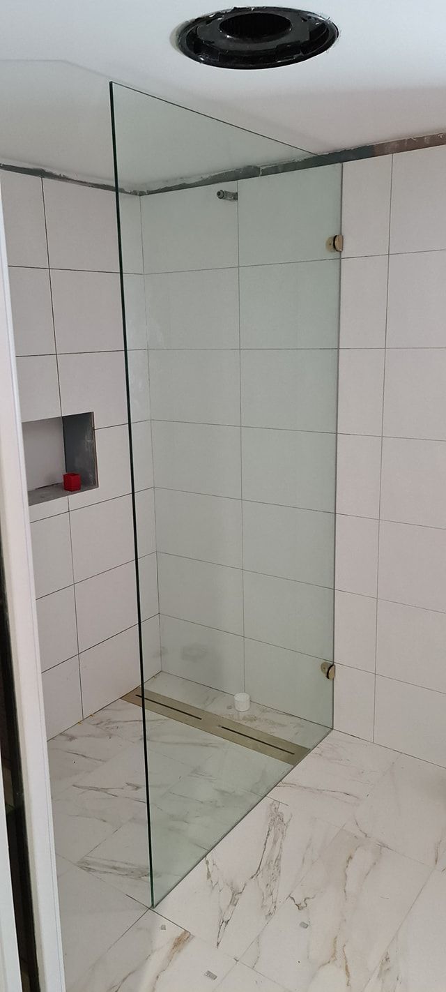 A bathroom with a walk in shower with a glass door.