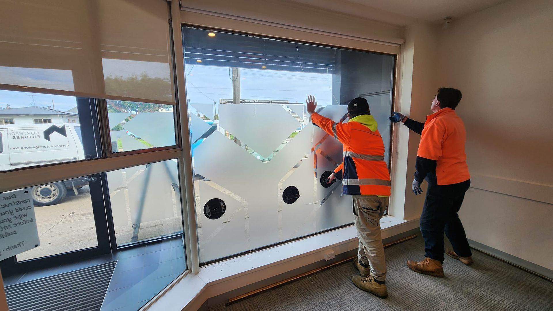 Two men are working on a window in a room.
