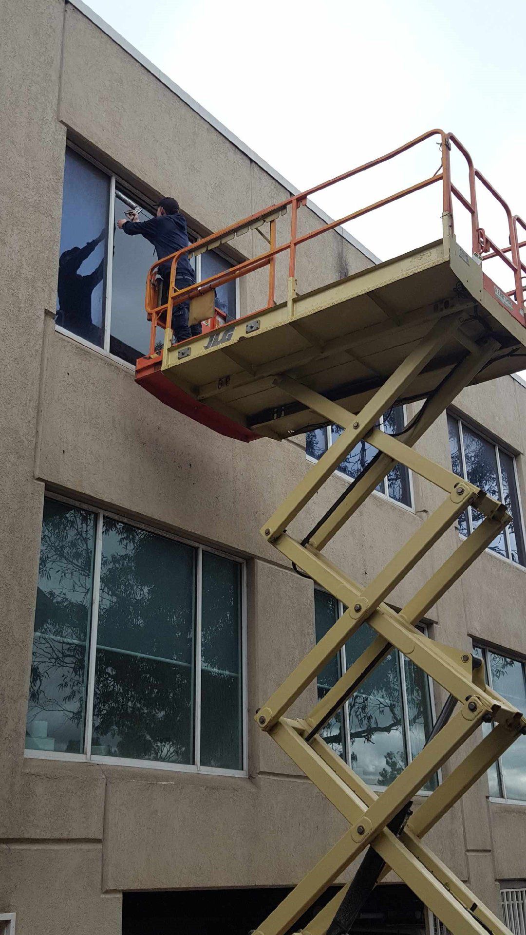 A man is cleaning windows on a scissor lift.