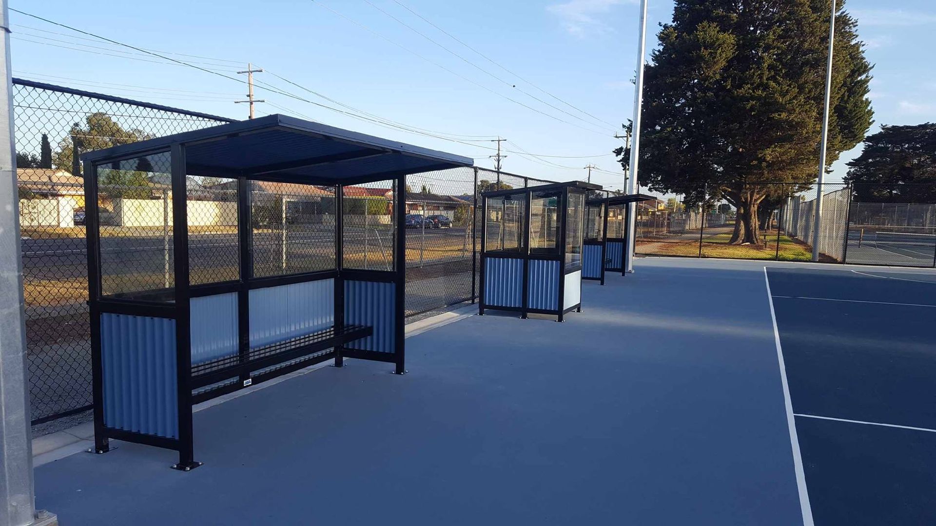 A row of bus stops next to a tennis court.