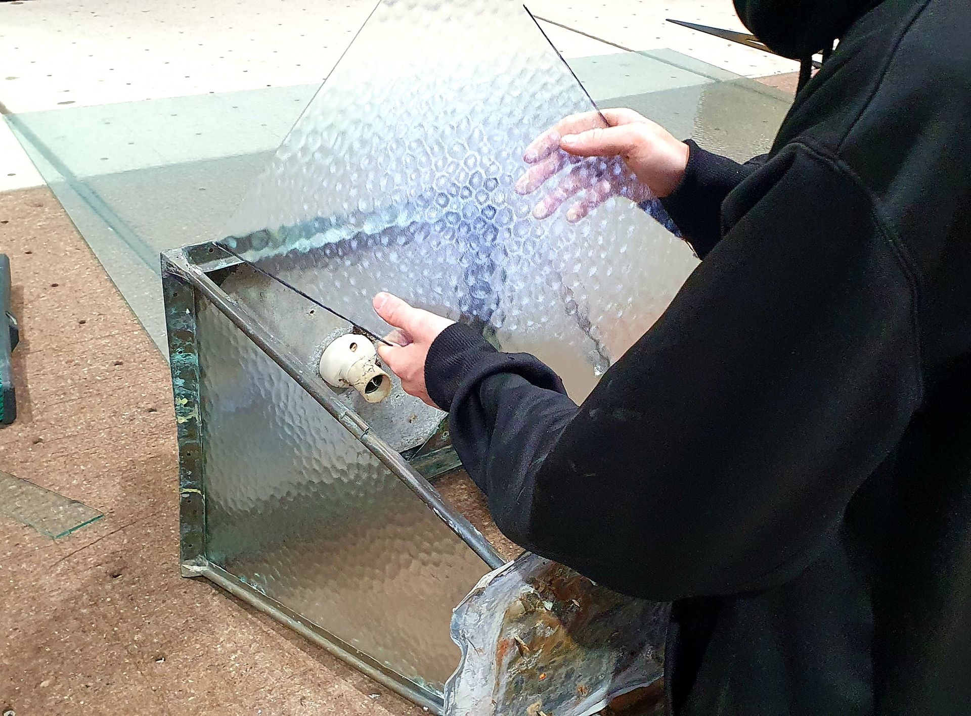 A person is cleaning a glass aquarium with a brush.