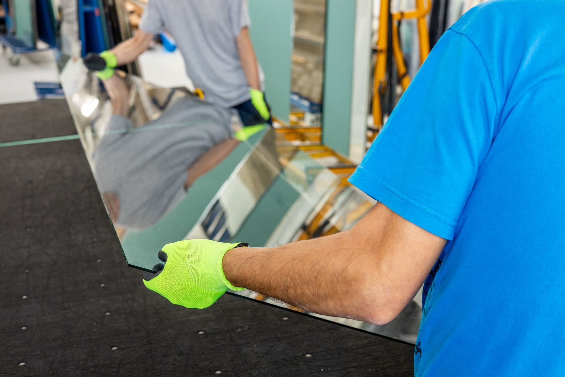 Glaziers place a large sheet of thick glass on the table by hand.