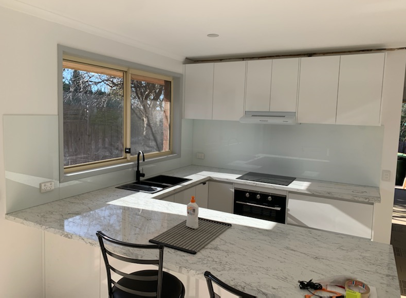 White kitchen with granite countertops, black appliances, and a window with natural light.