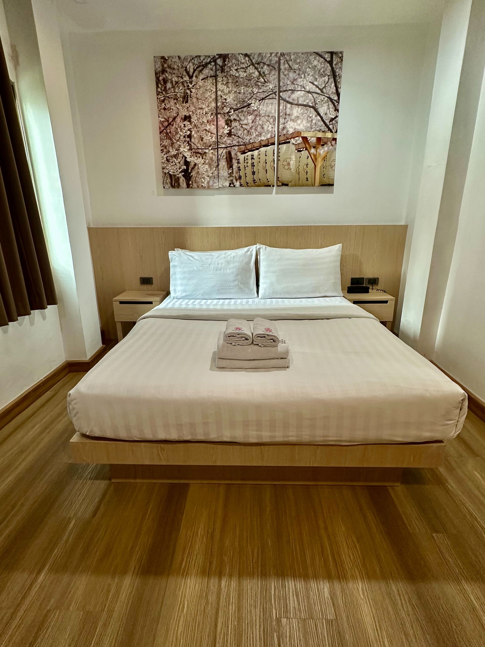 Bedroom with light wood furniture and a bed, featuring a painting above it.