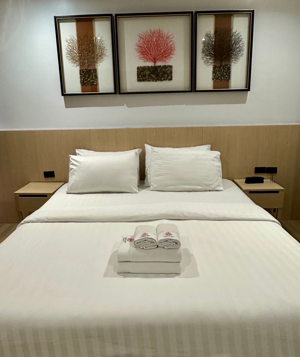 Bedroom with a made bed, nightstands, and artwork of abstract trees above.