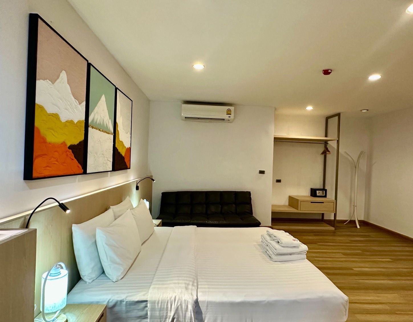Modern hotel room with a bed, sofa, and mountain art.