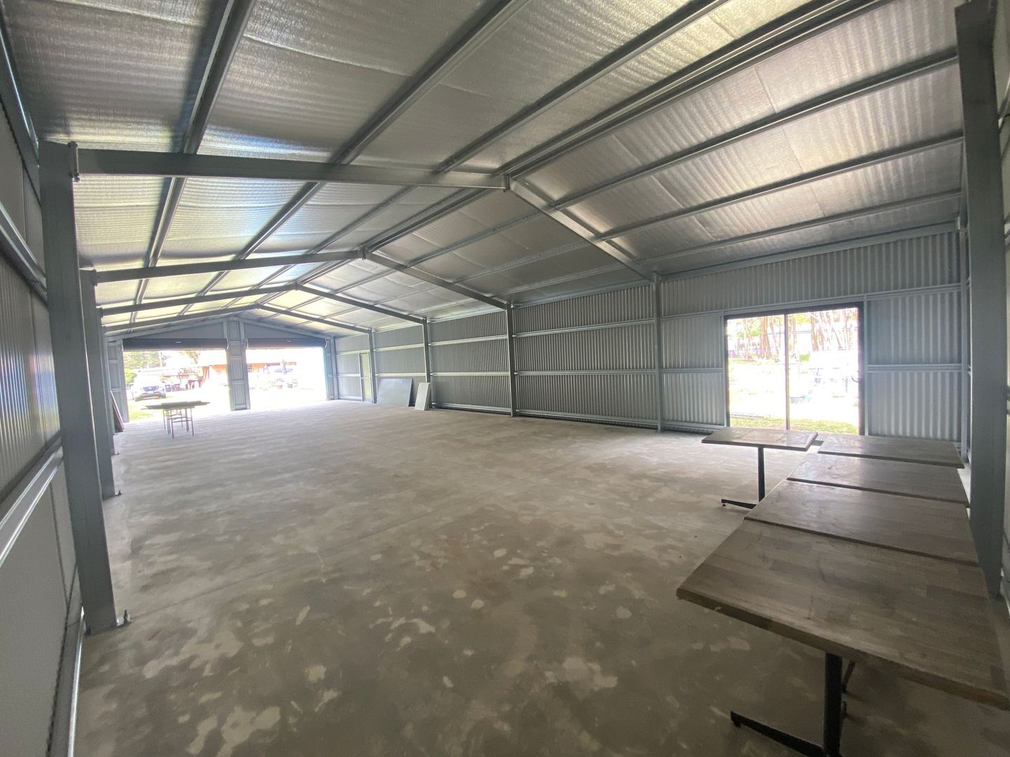 Empty metal warehouse interior with corrugated walls, open doors, and a concrete floor