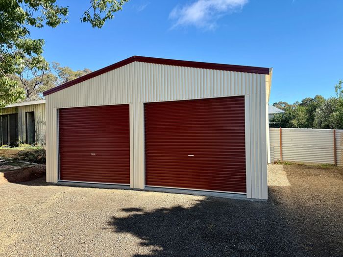 Blue metal shed in a grassy rural yard under a partly cloudy sky