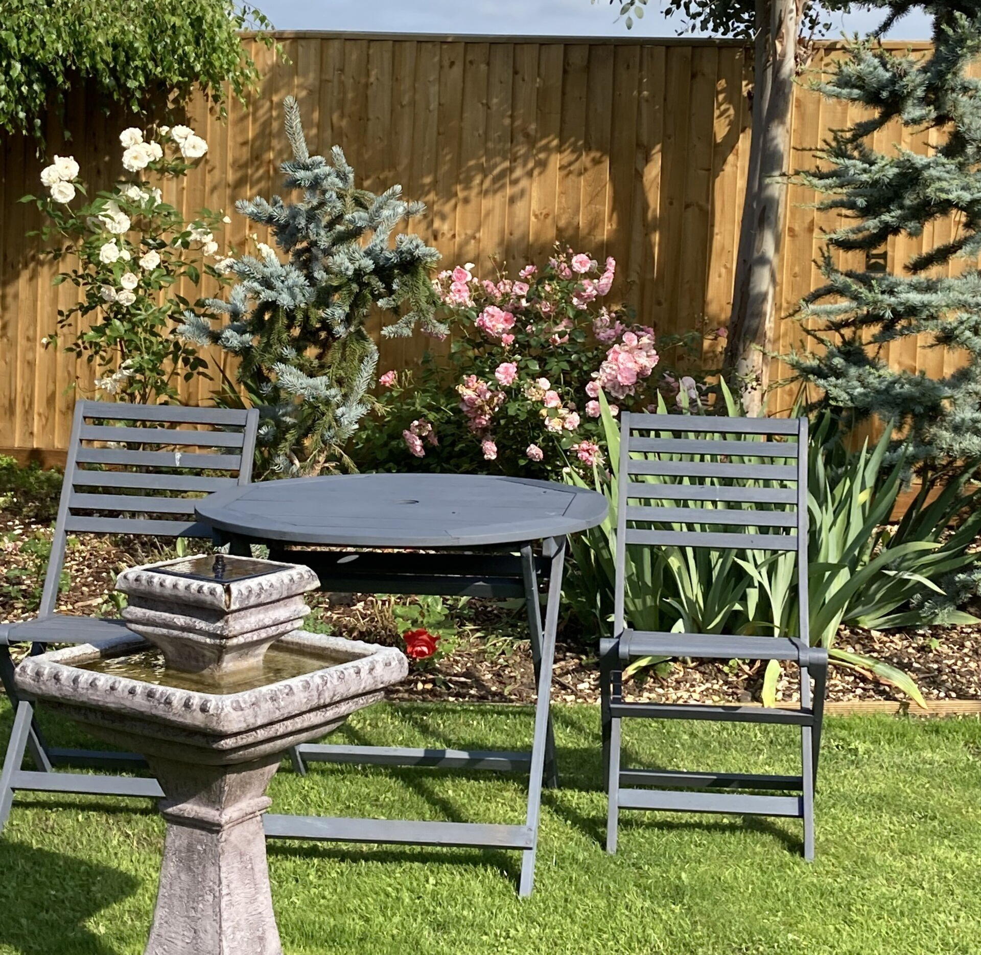 A garden with a table and chairs and a fountain