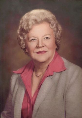 A woman in a suit and pink shirt is posing for a picture.