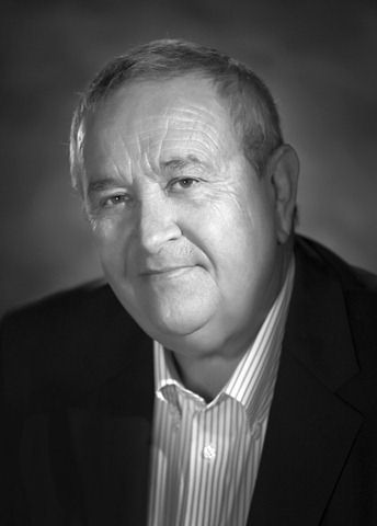 A black and white photo of a man in a suit and striped shirt.
