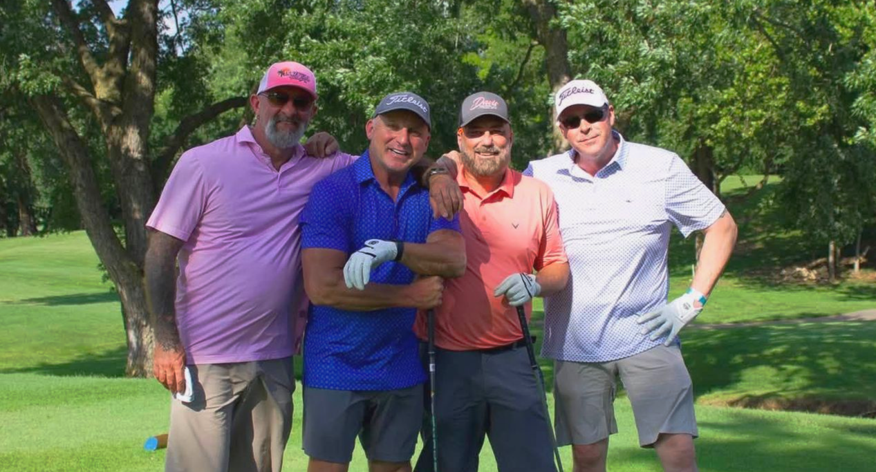 A group of men are posing for a picture on a golf course.
