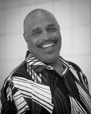 A man in a striped shirt is smiling in a black and white photo