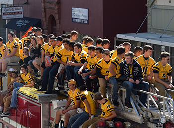 A group of football players are sitting on top of a fire truck