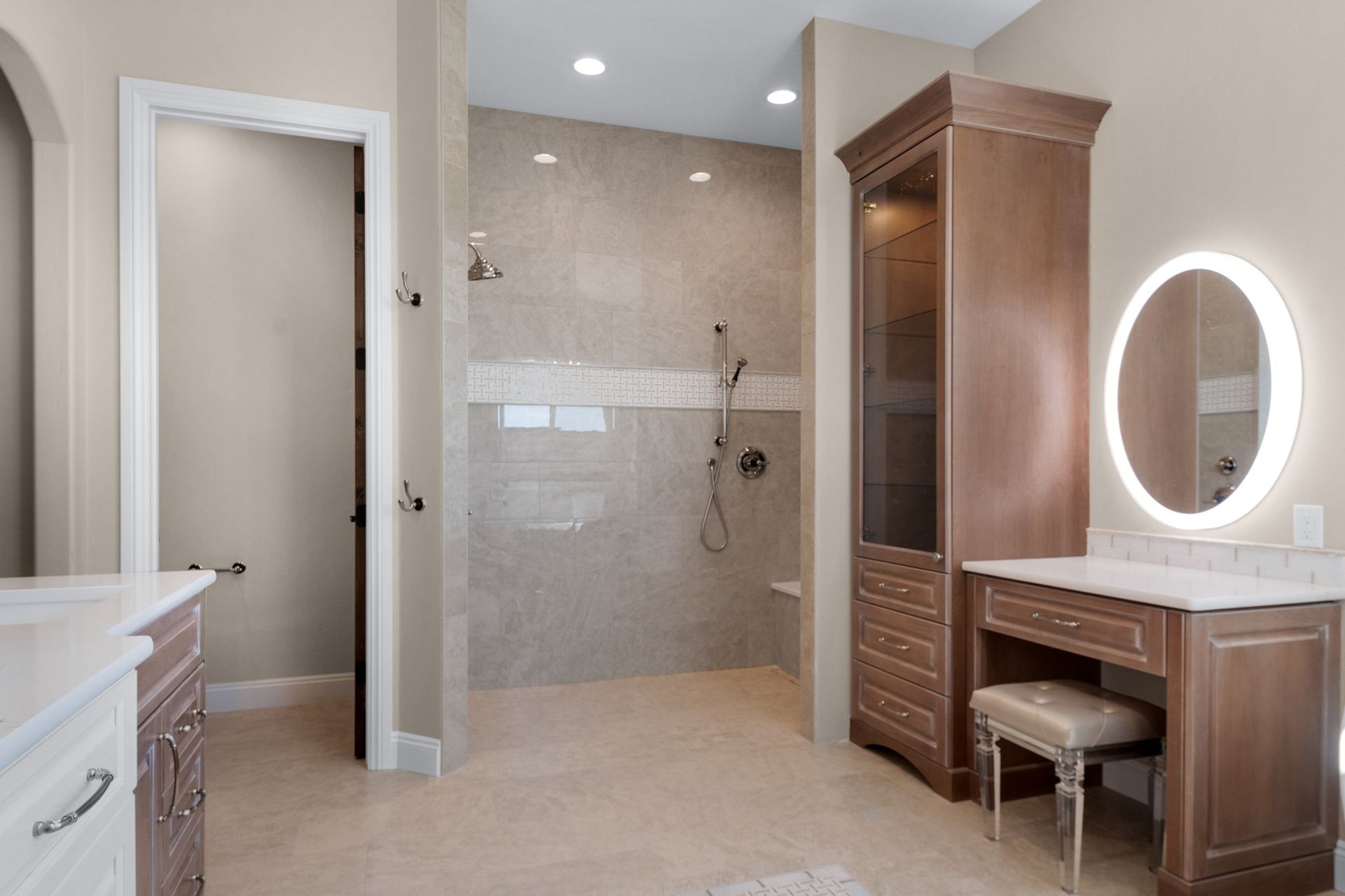 Spacious bathroom with a shower, vanity, and tall cabinet. Beige walls and light-colored floor.
