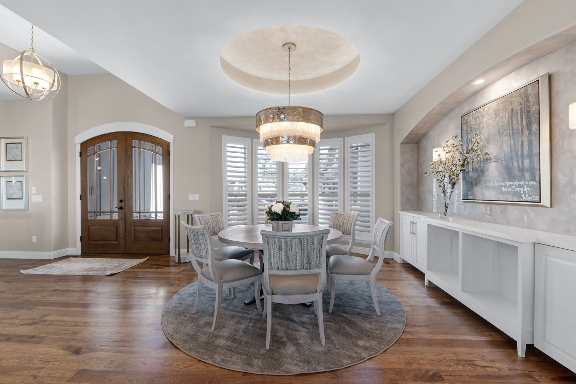 Elegant dining room with round table, chandelier, and built-in white cabinets.