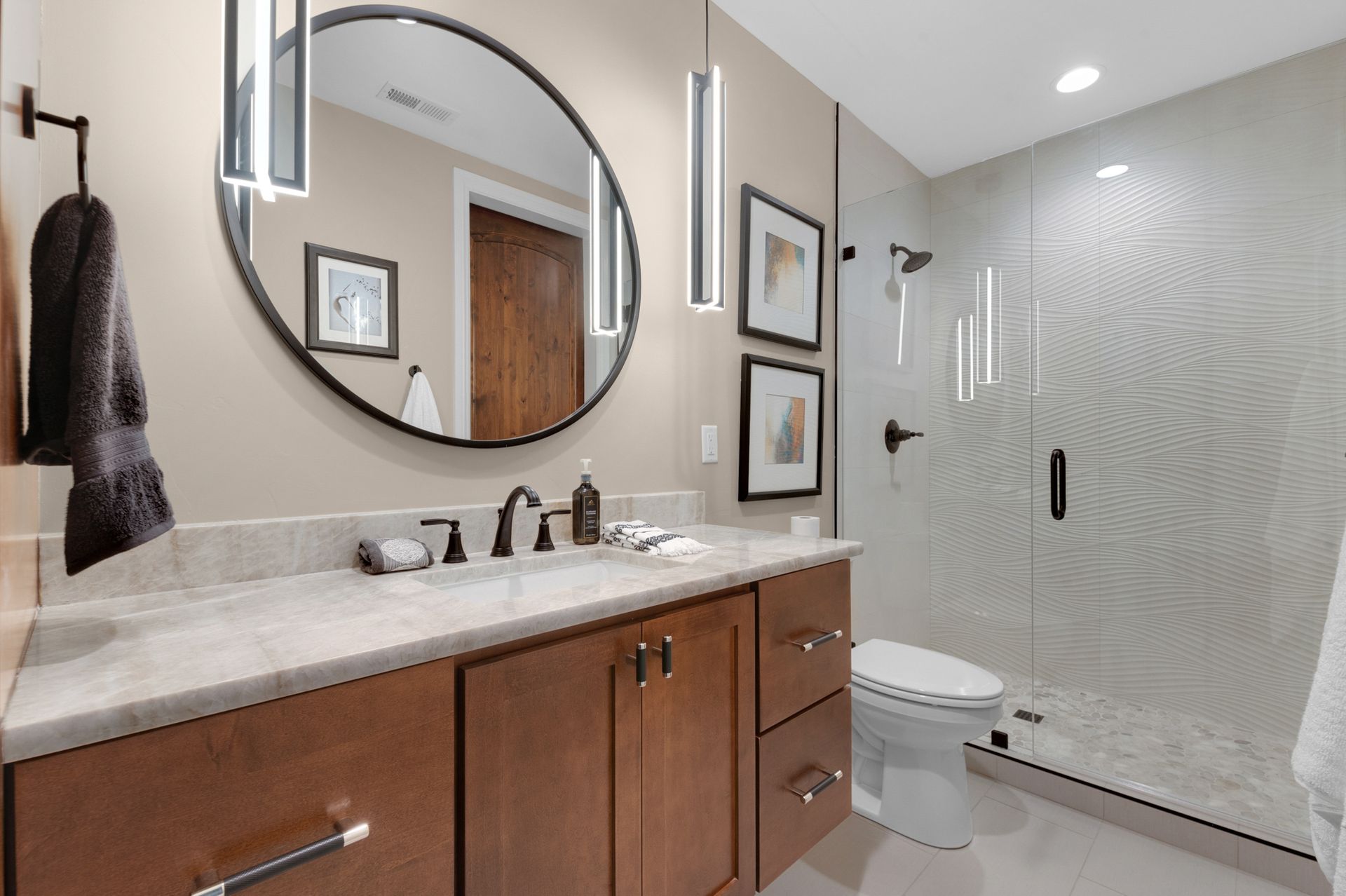 Modern bathroom with brown vanity, large mirror, and glass shower.