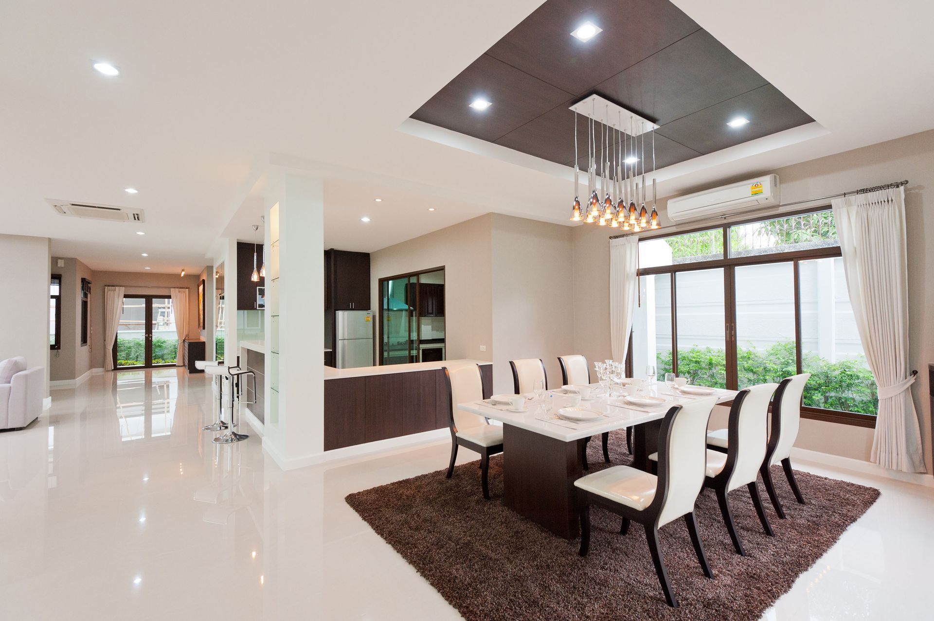 Spacious dining room with White walls and floors, and dark brown accents.