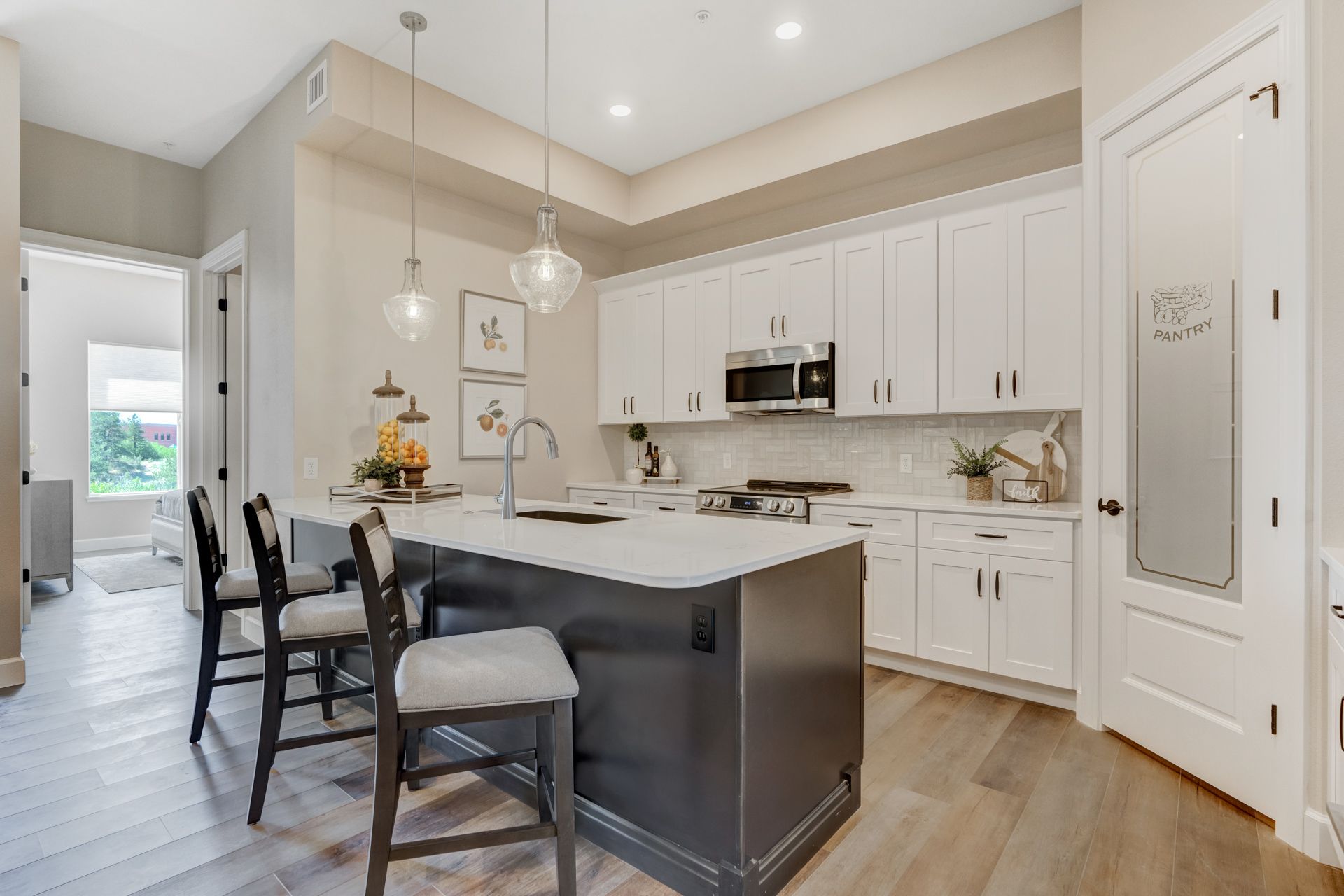 Elegant dining room with a wooden table, bench, and chairs, next to a light-filled kitchen.